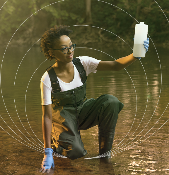 Student grabbing samples of water in foreground with impact circles in background 